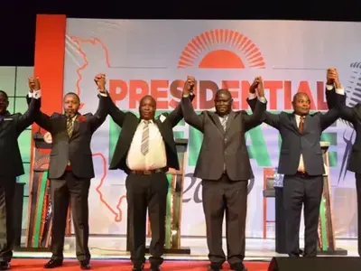 Candidates on stage holding arms up 